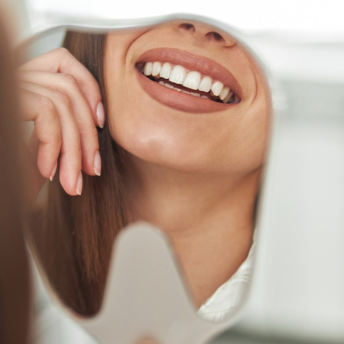 happy-young-woman-smiling-checking-out-her-perfect-healthy-teeth-mirror-close-up-dentist-office